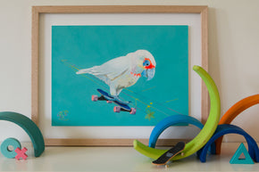 A Corella riding a skateboard. Australian bird Art print for kids bedroom by Good Art. Australiana themed artwork for kids. Artwork sits on shelf with wooden toys.