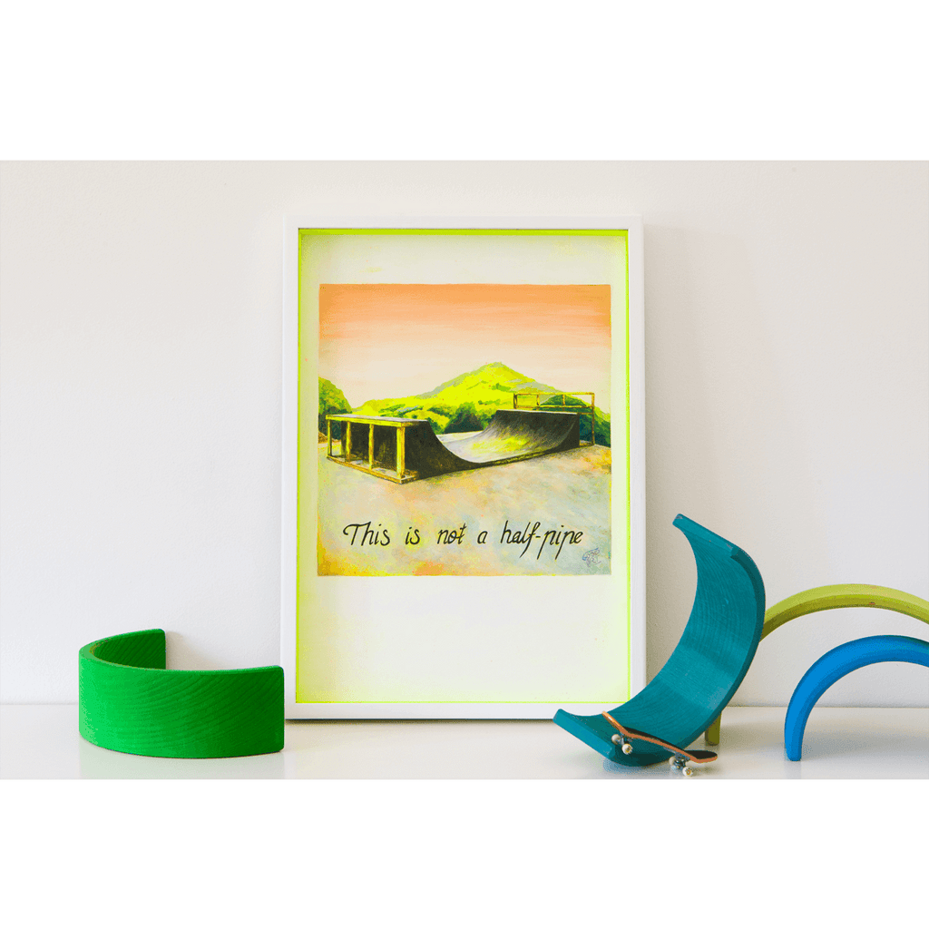 A painting of a half-pipe against a scenic mountain landscape with the words underneath ‘This is not a half-pipe’ Original artwork painted by Australian artist Jaelle Pedroli for Good Art framed and sits on a shelf.