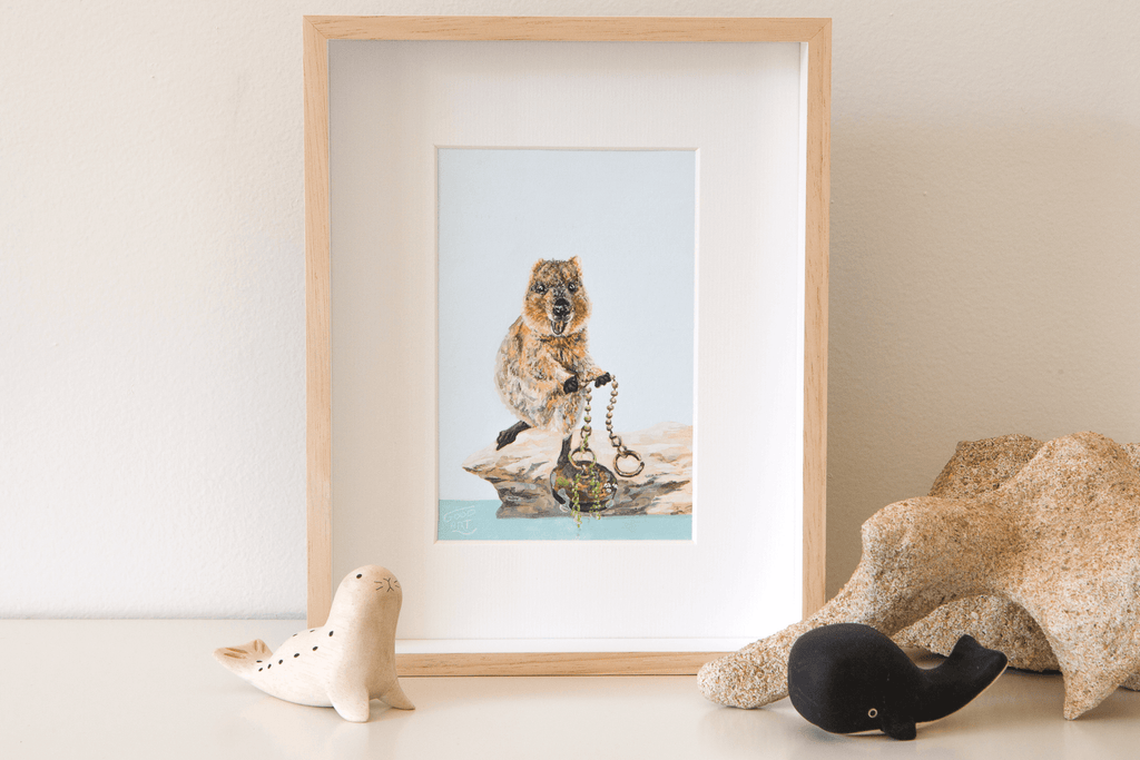 Standing on the rocks at the edge of The Basin, Rottnest Island a quokka is pulling a large sink plug from the sea. An original artwork of the quokka at The Basin is framed and sits on a shelf.