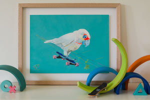 A Corella riding a skateboard. Australian bird Art print for kids bedroom by Good Art. Australiana themed artwork for kids. Artwork sits on shelf with wooden toys.