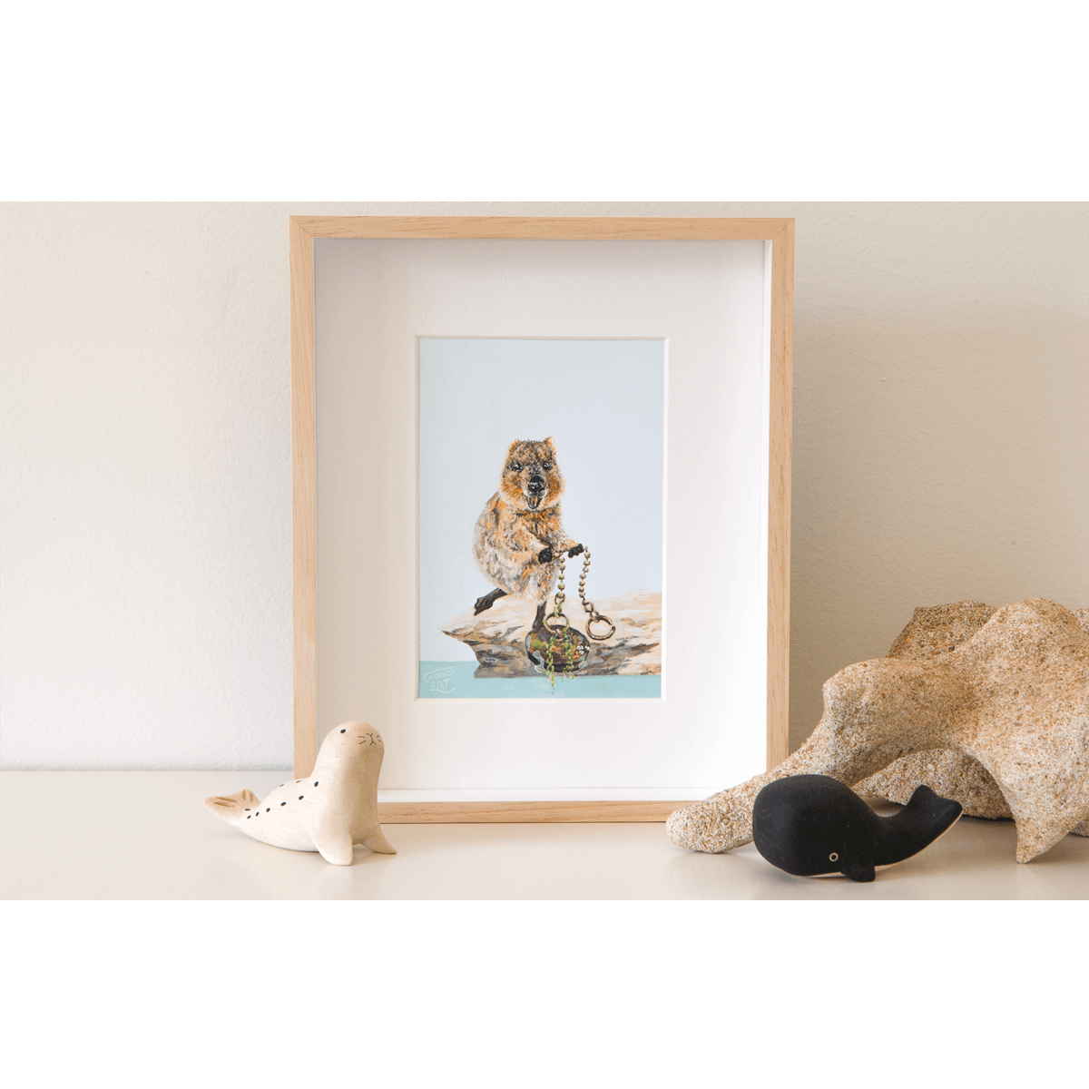 Standing on the rocks at the edge of The Basin, Rottnest Island a quokka is pulling a large sink plug from the sea. An original artwork of the quokka at The Basin is framed and sits on a shelf.
